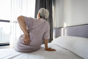 Stressed asian senior woman suffering from backache,sitting on bed massage her waist pain