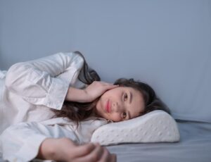 Woman sleeping on a memory foam pillow, showcasing the use of an orthopedic pillow for improved sleep quality and comfort.