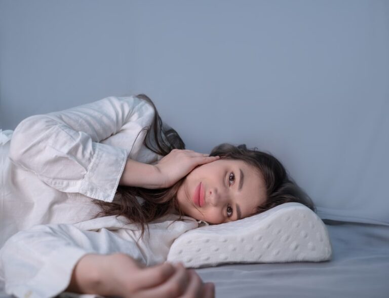 Woman sleeping on a memory foam pillow, showcasing the use of an orthopedic pillow for improved sleep quality and comfort.